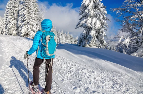 Mujer joven en chaqueta del amanecer senderismo con zapatos de nieve — Foto de Stock
