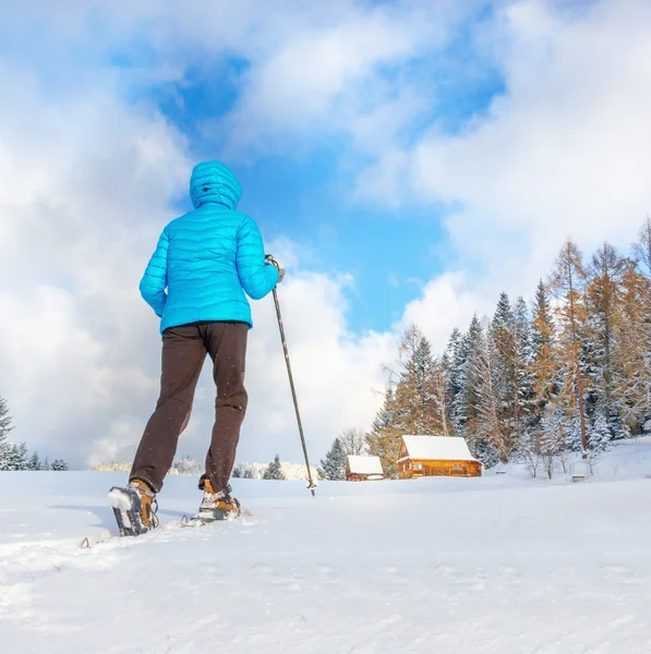 Mujer joven corriendo con raquetas de nieve en nieve clara —  Fotos de Stock