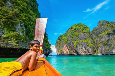 Thai boy on colorfull longtail boat in Thailand clipart