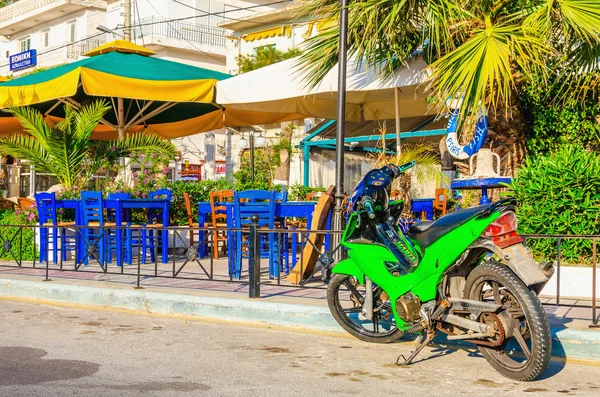 Green motorbike in front of Greek restaurant — Stock Photo, Image