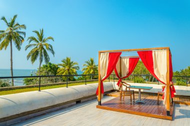 Pergola ile masa, sandalye ve kırmızı perdeler