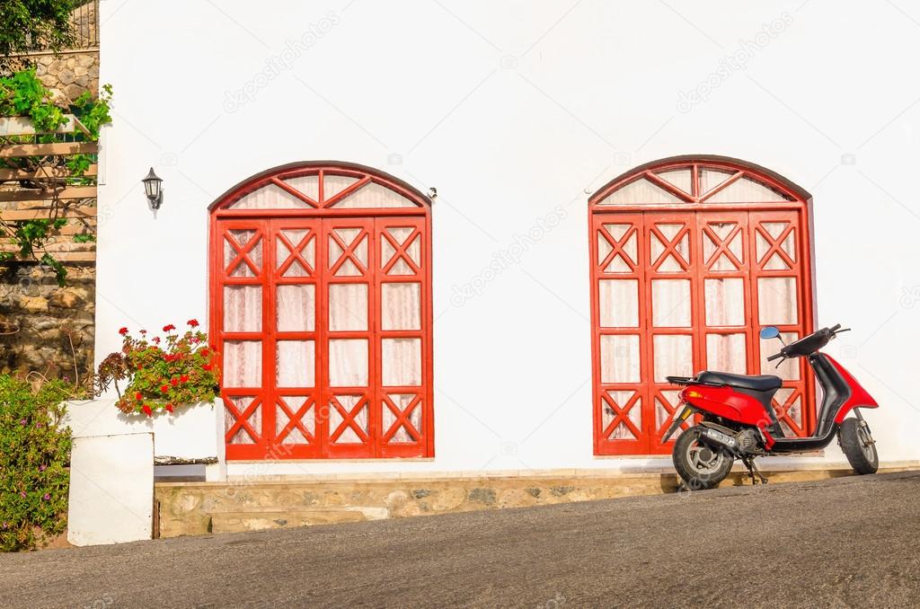 Red motorbike in front of typical Greek house