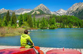 Young man at pier mountain lake with high peaks