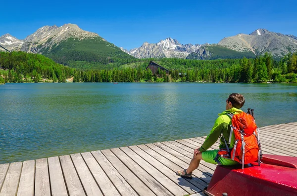 Man with backpack sitting on red boat — Stock Fotó