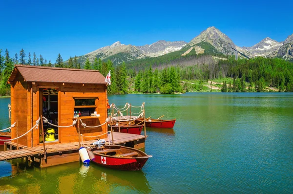 Wooden hut and red boats on mountain lake — Stock fotografie