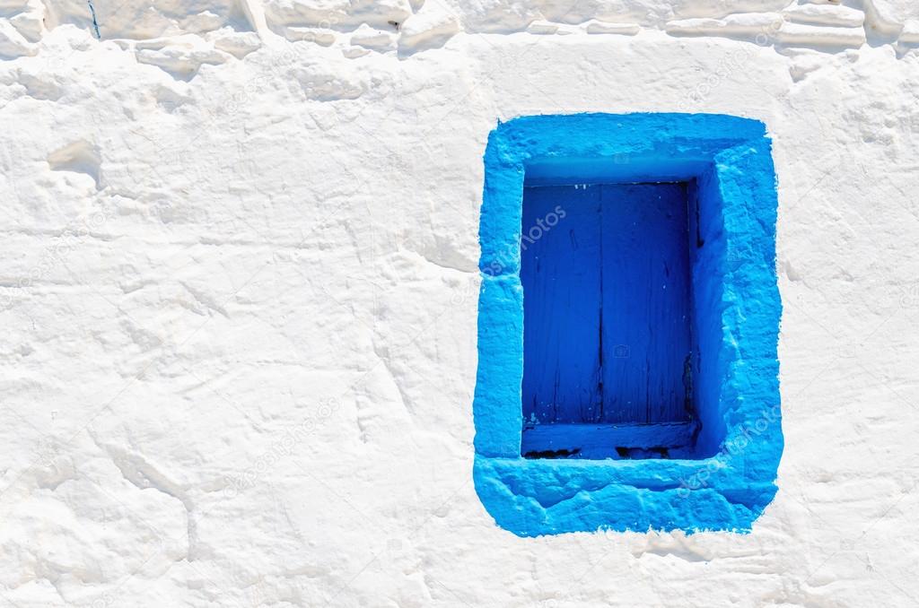 Blue wooden window on white stone wall, Greece