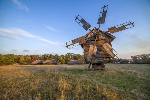 old windmill in a field at sunset