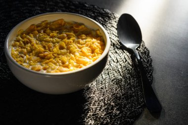 Detail of sunlit breakfast table with bowl with corn flakes cereal.