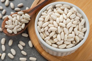 Beyaz fasulye taneleriyle dolu bir kase. Tahta kaşık ve bambu desteği ayrıntıları.