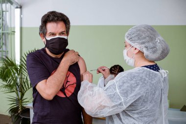 Sao Paulo, Brezilya, Mayıs 05, 2021: Yetişkin adam sağlık kliniğinde aşılanıyor..