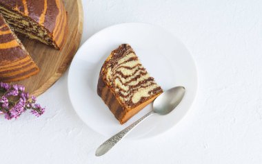 Beyaz arka planda zebra pastası. Beyaz tabakta bir parça sünger keki. Uzayı kopyala Mutfak konsepti. Üst görünüm.