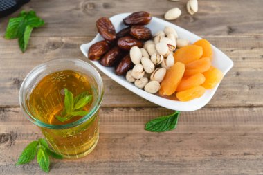 Kurutulmuş meyve tepsisi, hurma, fıstık ve ahşap tabanda çay bardağı ile kurutulmuş kayısı. Boşluğu kopyala.