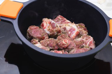 Siyah bir güveçte pişirilmeye hazır kuzu eti. Yemek pişirme konsepti.