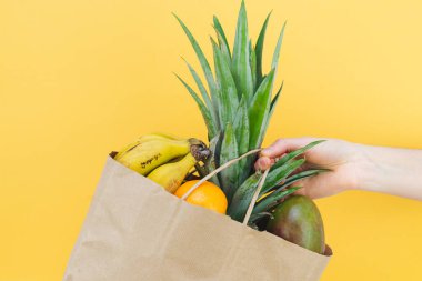 Sarı arka planda meyveli kese kağıdıyla. Boşluğu kopyala.