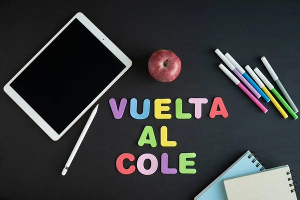 School materials with the phrase REGRESO A CLASE in Spanish on a black background. Copy space.