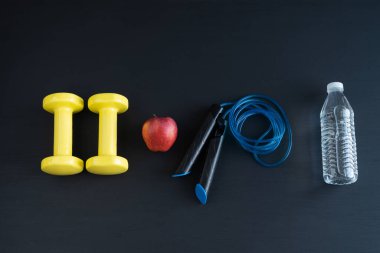 Ev egzersizi için siyah arka planda dambıllar ve ip atlama. Boşluğu kopyala.