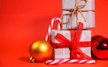 Alicante, İspanya - 15 Aralık 2019: Kırmızı arka planda kırmızı yay ve iple eski gazetelere sarılı hediyeler