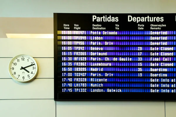 Porto, Portugal- January 8, 2020: Information panel for departures and arrivals next to a clock at the airport of Porto