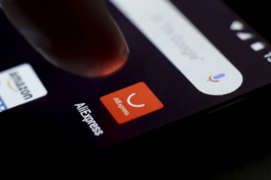 Alicante, İspanya... 13 Eylül 2019: Siyah cep telefonu ekranında Aliexpress simgesine parmak basma. Arka planda ebay simgesi.
