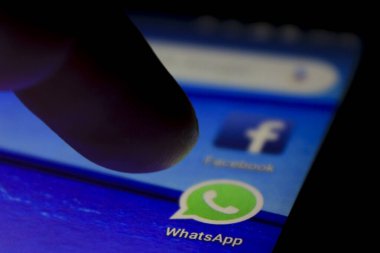Alicante, İspanya - 6 Temmuz 2019: mavi cep telefonu ekranında Whatsapp simgesine parmak basma. Arkaplanda Facebook simgesi.