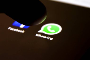 Alicante, İspanya - 6 Temmuz 2019: siyah cep telefonu ekranında Whatsapp simgesine parmak basma. Arkaplanda Facebook simgesi.