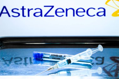 Madrid, İspanya... 7 Ocak 2020 'de test tüpünün yanında aşı bulunan şırınga. Arka planda beyaz arka planda Astrazeneca Laboratuvarı logosu.