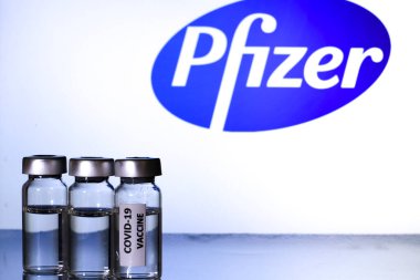 Madrid, İspanya 23 Şubat 2021 'de beyaz zemin üzerinde covid-19 aşısı olan cam şişeler. Arka planda Pfizer İlaç Şirketi logosu var..