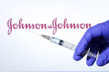 Madrid, İspanya... 7 Ocak 2020 'de elinde Covid aşısı olan mavi ameliyat eldiveni vardı. Arka planda Johnson ve Johnson Laboratuvarı logosu beyaz arka planda.