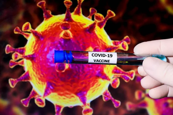 Medical professional hand with surgery glove holding Covid-19 virus vaccine and covid virus microscopic image in the background