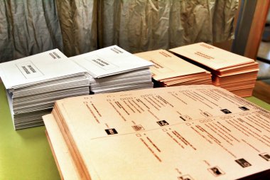 Madrid, İspanya - 10 Mart 2021 İspanya 'daki bir sandık merkezindeki ahşap bir masada oy kullanmak için zarflar ve zarflar.