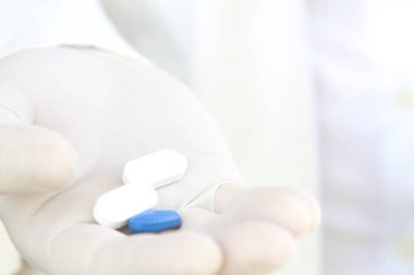 Elinde haplar olan beyaz eldivenli bir erkek.