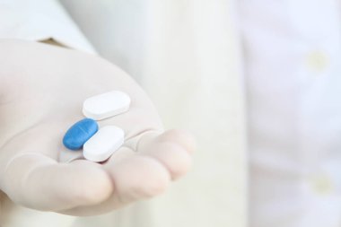 Elinde haplar olan beyaz eldivenli bir erkek.