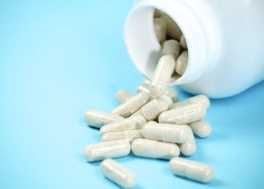 Mavi arka planda beyaz kapsül şişesi