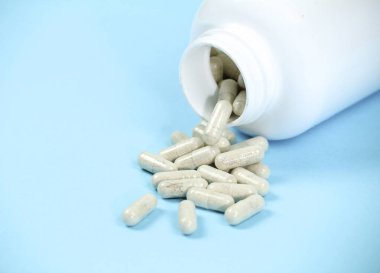 Mavi arka planda beyaz kapsül şişesi