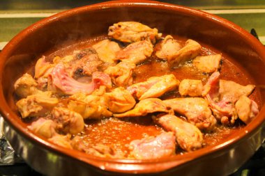 Tavşan ve tavuk eti, Costra adında geleneksel bir İspanyol yemeği yapmak için kilden bir tencerede kızartılıyor.