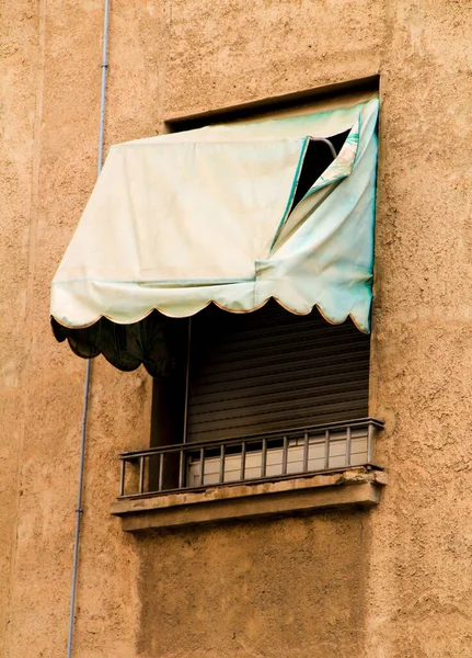 Old window with broken green awning in Spain