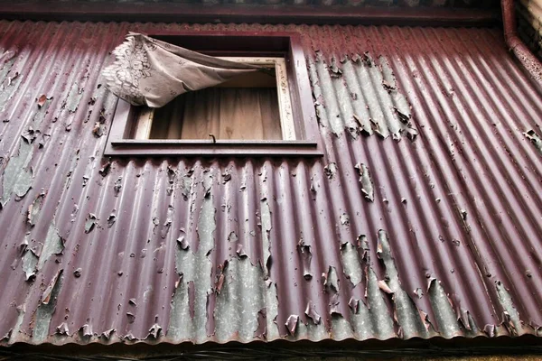 Old metal house facade with rusty window with curtain in Porto, Portugal