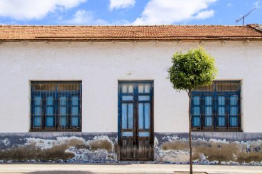 Torrellano köyü, Elche, Alicante, İspanya 'da küçük bir evin mavi ahşap pencereleri ve kapısı olan eski renkli ve görkemli beyaz cephe. 