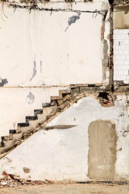 Yıkılmış binanın ön cephesinde merdivenler ve kapılar var.