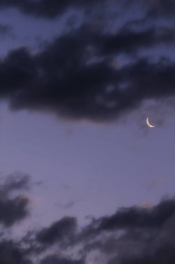 Gri bulutlu gökyüzü arkaplanı ve alacakaranlıkta hilal ay.