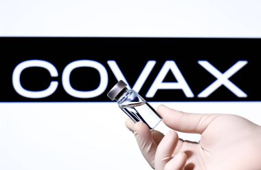 Madrid, İspanya... 23 Şubat 2021 Covid-19 aşısı ve beyaz arka planda Covax logosu olan el ele tutuşma şişesi..