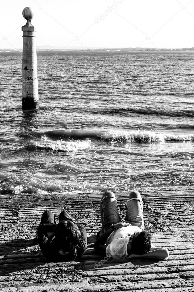 Tourists resting on the banks of Tagus river in Lisbon, Portugal