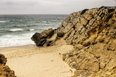 Portekiz ilkbaharında bulutlu gökyüzünün altında Guincho sahilinde kayalıklar ve kaya oluşumu
