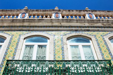 Baharda Lizbon sokaklarında eski renkli ve fayanslı ön cephelerde klasik sokak lambaları. Ön cephede çamaşır ipi asılı kıyafetlerle