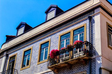 Baharda Lizbon sokaklarında eski renkli ve fayanslı ön cephelerde klasik sokak lambaları. Ön cephede çamaşır ipi asılı kıyafetlerle