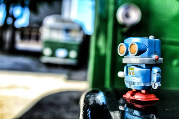 Toy robot on old bus school. Green color in the background.