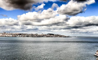 Arkaplanda bulutlu gökyüzünün altında 25 Nisan köprüsü