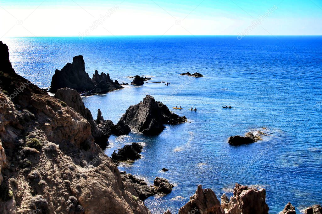 Reef of the Sirens in Cabo de GAta, Almeria, Spain in a sunny day of summer. People practicing canoeing in the background.