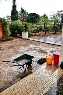 Kırsal alanda yağmurlu bir manzara ve yağmurla dolu yeşil el arabası.