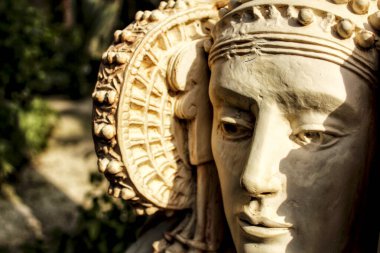 Lady of Elche stone bust in a garden under the sun clipart